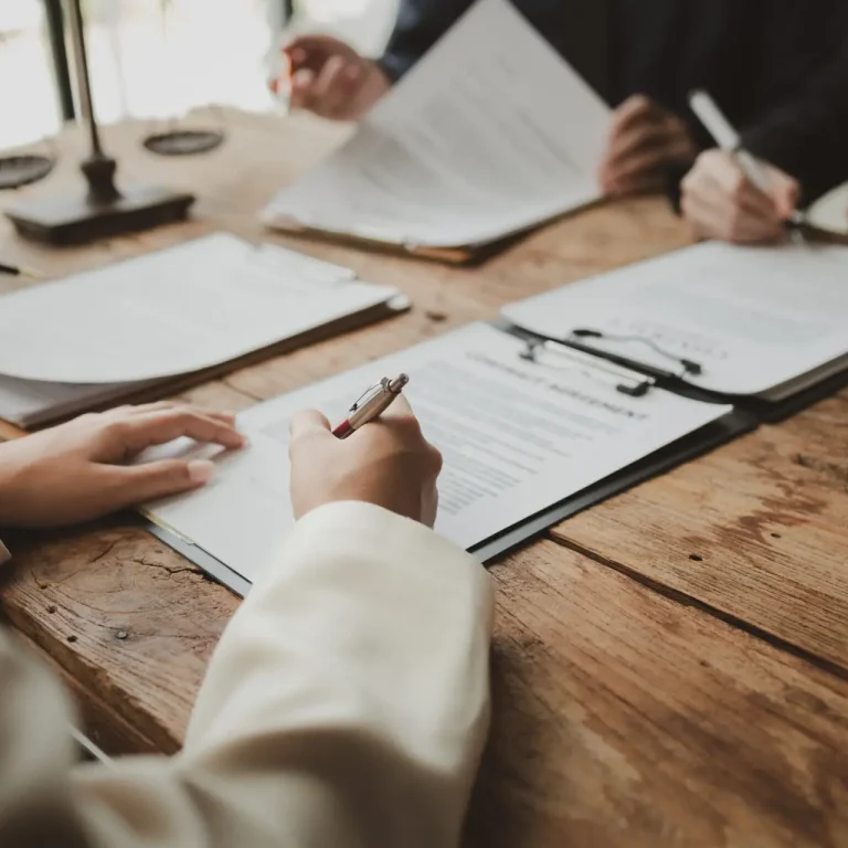 Business people negotiating a contract, discussing contract while working together in sunny modern office, unknown businessman and woman with colleagues or lawyers at meeting.